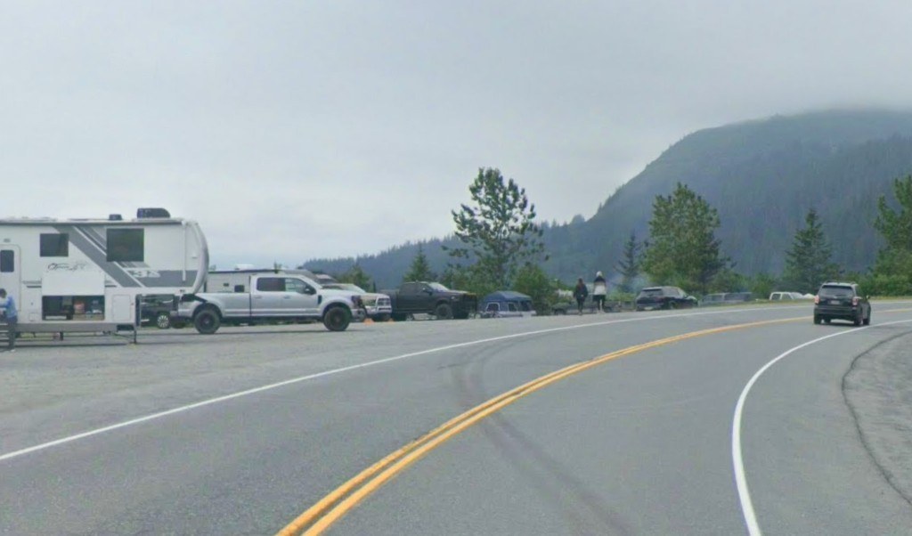 Rigs and trucks parked along the road at Allison Point, with a forested mountain behind them